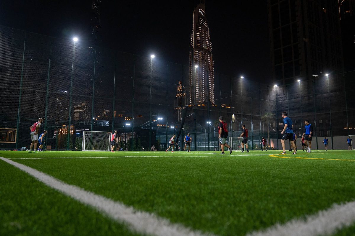 Floodlit five-a-side pitch at night, Burj Khalifa lit behind